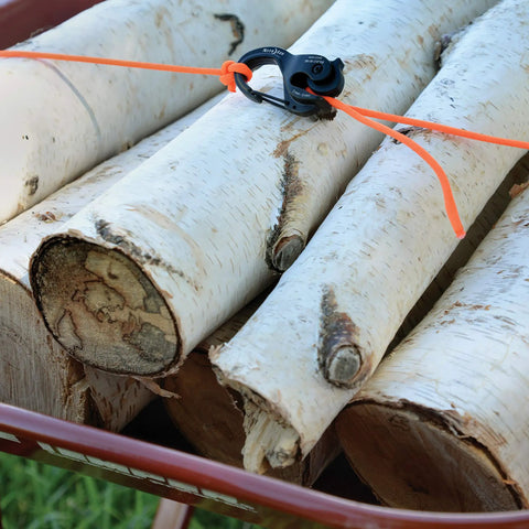 Beefy Aluminum Rope Tightener With Cam Lock And Quick Release securing birch logs, showing outdoor use for camping and hiking.