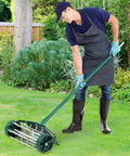 Person using Rolling Lawn Aerator 18 Inch With Fender And Tine Spikes, Anti Slip Handle, Manual Soil Aeration Tool on grass