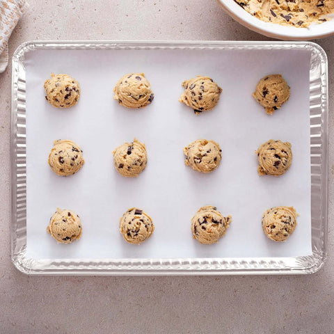 Disposable Aluminum Pans 5 Pack 13 By 17 Baking Sheets with cookie dough balls, heavy duty for easy no mess cleanup and reuse.