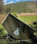 ATV Broadcast Spreader With Wireless Control And Adjustable Flow 80 lb Capacity in a field with tractor in the background