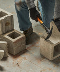 Person using IsoCore Pickaxe Mattock With Shock Absorbing Handle Dual Head For Roots And Rocks 1.5 Lb Heavy Duty Tool on concrete blocks