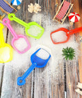 12 Piece Colorful Beach Sand Shovels For Kids Set With Plastic Summer Scoops For Toddlers Outdoor Digging Play Heavy Duty Garden Digging Toy Accessories shown on a wooden surface with sand and mini beach furniture.