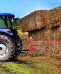 49 Inch Bale Spear With 3000 Lb Capacity Red Coated Bale Forks Hay Spike Attached to Tractor Near Haystack