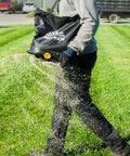 Person using Spyker 25lb Bag Spreader With Material Viewing Window And Easy Calibration System for spreading material on lawn.