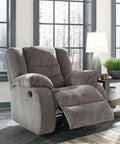 Plush gray recliner in living room setting near window with modern table lamp and green plant