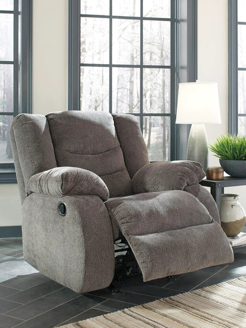 Plush gray recliner in living room setting near window with modern table lamp and green plant