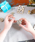 Four In One Wooden Puzzle Kit With Self Assembly Mini Mechanical Models Set Including Stocking Stuffer, Christmas Tree, Clock, And Bauble For Stress Relief, 3D Puzzles Fun For Ages 5 To 80, Plywood Construction, hands assembling round wooden ornament
