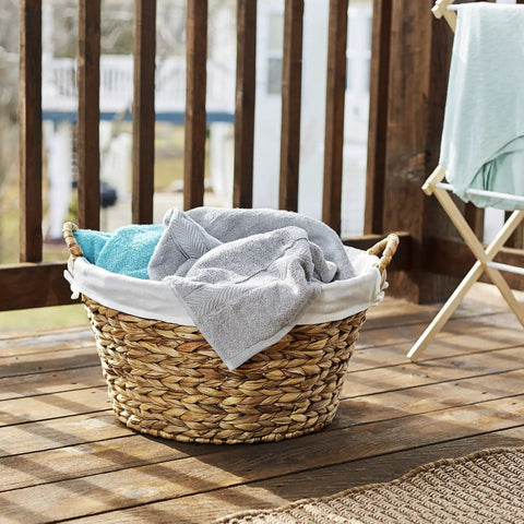 Round Wicker Laundry Basket With Easy Carry Handles, Water Hyacinth Construction, on porch with towels
