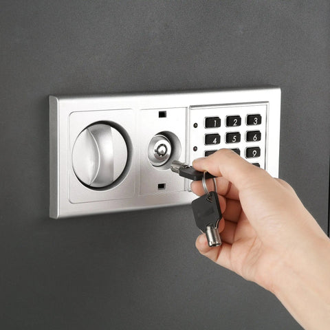 Hand using manual override key on Hidden In Wall Safe with Electronic Keypad for storing valuables securely in concealed wall vault.
