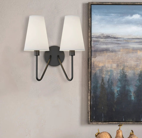 Two Light Wall Sconce Fixture in Black with Cream White Linen Lamp Shades, E12 Candelabra Base, wall mounted, beside artwork.