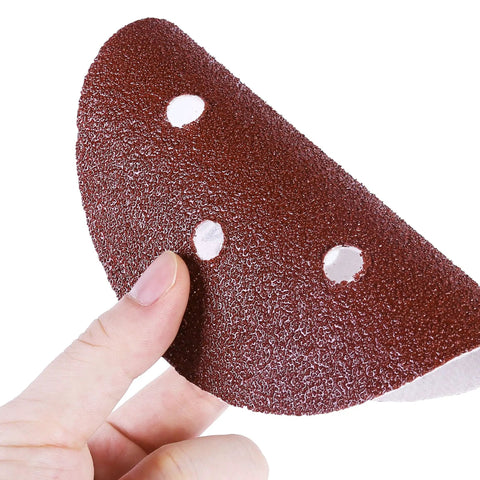 Hand holding a single sanding disc from 130 Piece Pro Grade 6 Inch Sanding Discs Set With 6 Hole Pattern Grit Range 40 To 2000 For Random Orbital Sander Hook And Loop Aluminum Oxide Sandpaper Assortment Anti Clog Coating Resin Bond For Fast Smooth Finishes, showing its texture and holes.