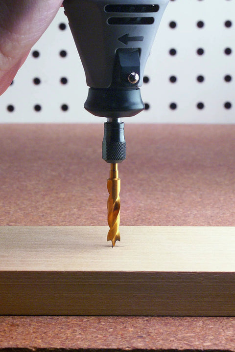 Close-up of a rotary tool with a Brad Point Drill Bit Set Titanium Coated 4 Pieces for Woodworking drilling into wood.