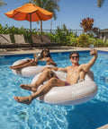 Adults relaxing in pool with Motorized Pool Tube Float For Adults Pro 3.0 With 66W Motor Joystick Steering Phone Holder And Cup Holder Blue Finish Lets You Glide Turn And Cruise Across The Water All Day.