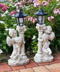 Lit Solar Angel Garden Statue With Roma Pillar For Outdoor Decor And Lawn Or Patio Nineteen Point Seven Inch Left Facing Angel That Lights Up At Night A Perfect Christian Gift For Garden Yard Or Porch, featuring two solar statues in a flower garden.