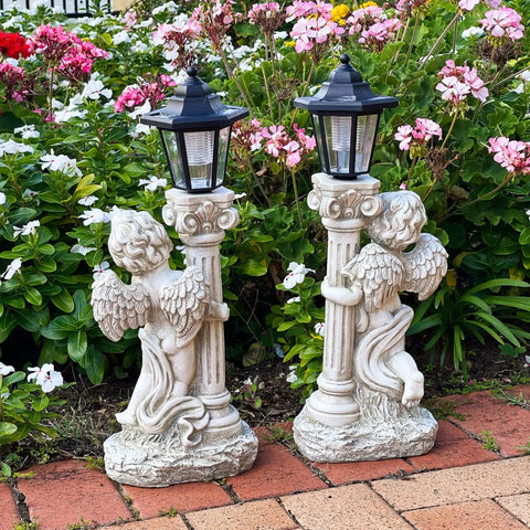 Lit Solar Angel Garden Statue With Roma Pillar For Outdoor Decor And Lawn Or Patio Nineteen Point Seven Inch Left Facing Angel That Lights Up At Night A Perfect Christian Gift For Garden Yard Or Porch, featuring two solar statues in a flower garden.