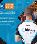Back view of cyclist wearing Klean Athlete jersey in gym, featuring NSF Certified for Sport, emphasizing trust by athletes.