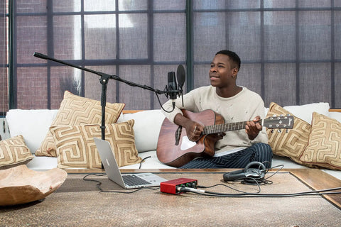 Person using Scarlett Solo 3rd Gen USB Audio Interface Bundle With LyxPro Cardioid Condenser Mic for home studio recording.