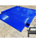 Heavy Duty Low Profile Drum Scale Built Tough With Smooth Hinged Ramps For No Sweat Barrel Rolling And Rock Solid Weighing Capability Up To 5000 Pounds With Spot On One Pound Accuracy NTEP Approved on a blue platform with digital display.