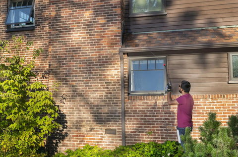 Person using Go-To Rechargeable Power Wand With 3 Way Spray Nozzle And 3.6V Lithium Ion Battery on brick house wall