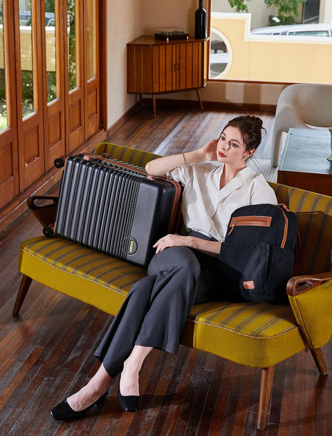 Woman sitting with Airline Approved Carry On Luggage 22x14x9, 20 Inch ABS Hard Shell Suitcase With TSA Lock beside her on a retro couch.