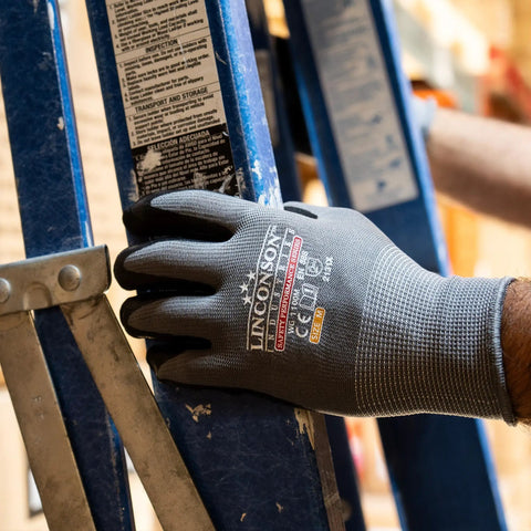 Worker wearing 12 Pack Safety Performance Series Work Gloves For Construction And Mechanics Heavy Duty With Breathable Flex handling ladder.