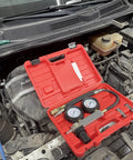 Front view of red HFS cylinder leak detector test kit with dual gauges and hoses on engine bay