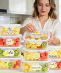 Woman stacking clear containers labeled 'Homemade Sweetness' with mixed fruit in a kitchen.