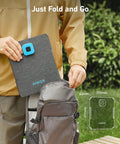 Person placing Solix PS30 Foldable 30W Solar Panel Charger in backpack, showing compact size and ease of use for camping.