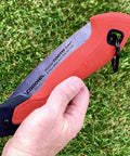 7 Inch Folding Pruning Saw With Fast Cut Razor Tooth Blade Heavy Duty Hand Tool held in hand, showcasing ergonomic grip on grass.