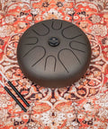 Super Responsive 16 Inch Steel Tongue Drum With Eight Soothing Notes on a patterned rug, includes pro grip mallets.