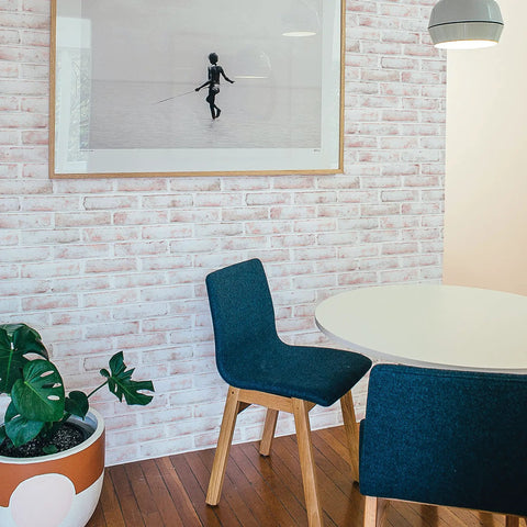 Dining area with Black Brick Textured Peel And Stick Wallpaper Removable Self Adhesive For Easy Diy Wall Makeovers No Mess No Glue 20.5 Inch By 16.5 Foot Realistic Brick Look Made In USA, round table, and blue chairs.