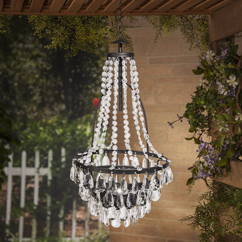 Lit Solar Metal Chandelier For Outdoor Patio with clear acrylic beads in a garden setting, 33-inch hanging decor, rustic vibe.