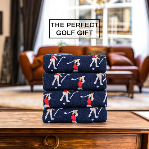 Stack of navy blue funny angry golfer socks for men size ten to thirteen, hilarious golf gift displayed on a wooden table.