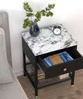 Black and white marble top nightstand with open drawer, decorative items, and a vase on a wooden floor