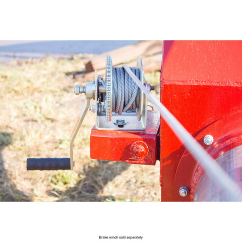 Side view of a manual winch on a red trailer frame, showing a metal spool with wrapped steel cable and crank handle.