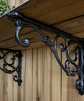 4 Pack Badass Cast Iron Shelf Brackets 11 By 7.5 Inch Antique Black Corbels With Screws And Anchors showing intricate vine pattern under wooden shelf.