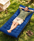 Man relaxing on Extra Wide Camping Cot for Adults With Mattress, Heavy Duty 1200D Oxford Fabric Folding Cot, outdoors