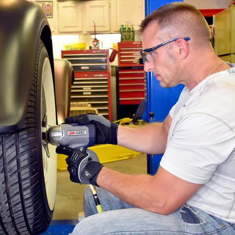 Man using half inch pneumatic impact wrench with 750 ft lbs torque three speed regulator for lug nut removal on car tire