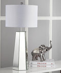 Janice Modern Art Deco Mirror Chrome 32 Inch Table Lamp Set Of 2 With Off White Cotton Shade displayed beside books and silver elephant sculpture