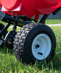 Close-up of the 10 inch pneumatic tires on the Commercial Walk-Behind Broadcast Spreader With 65 Lb Capacity For Grass Fertilizer And Seeds, Side Spread Control, Even Coverage, Ideal For Lawn Care And Landscaping.
