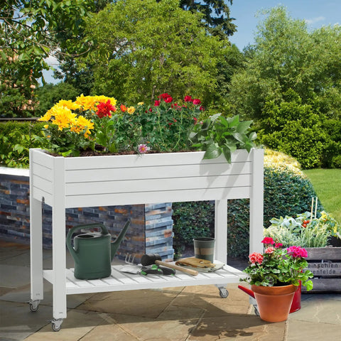 Elevated Garden Bed Kit With Legs And Wheels Large Resin Planter Box Stand With Drain Plug And Storage Shelf Perfect For Plants Vegetables Fruits Outdoor Durable Grayish White in garden setting with plants