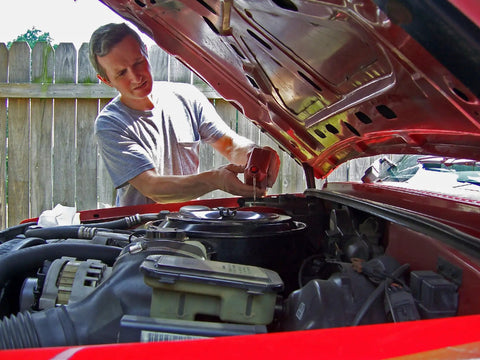 Mechanic installing Extra Guard CH10246 Spin On Engine Oil Filter For 10K Mile Change on a car engine in a garage.