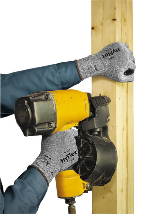 Person using multipurpose foam nitrile coated work gloves with breathable liner while holding a nail gun and wooden board, size extra large.