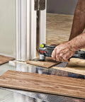 Man using AW400 F80 Sonicrafter 4.2 Amp Oscillating Multi Tool With 9 Accessories to trim wood flooring near a door frame.