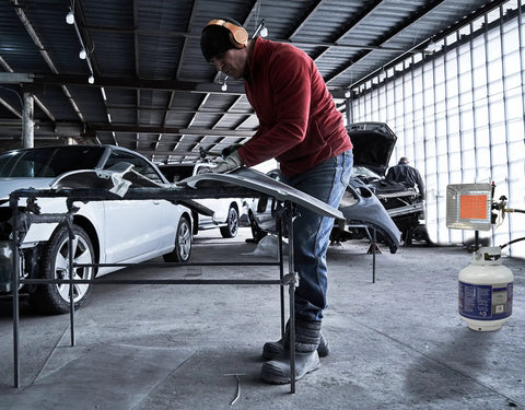 Person working in a garage with GS4200EP 13,000 BTU Propane Tank Top Heater Built For Outdoors, Tough Jobsites, and Campsites in use.