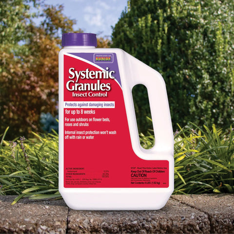 Insect Control Systemic Granules container on outdoor ledge, red label, garden background