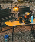 Portable folding table legs crafted from skateboards supporting coffee setup in outdoor camping scene.