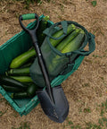 Mini Digging Shovel Built Tough With Heavy Duty Carbon Steel Head And Serrated Blade placed on zucchini box, outdoor setting.