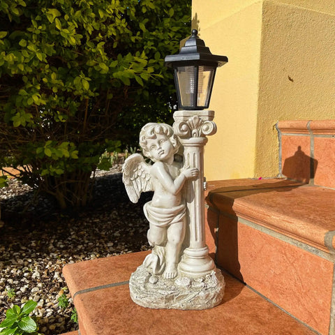 Lit Solar Angel Garden Statue With Roma Pillar for outdoor decor on steps with greenery.
