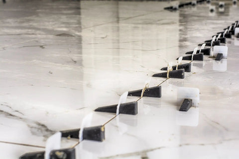 White 1mm Tile Leveling System Tabs Pack Of 500 For Perfect Flat Installs in use on a tiled floor, preventing lippage.